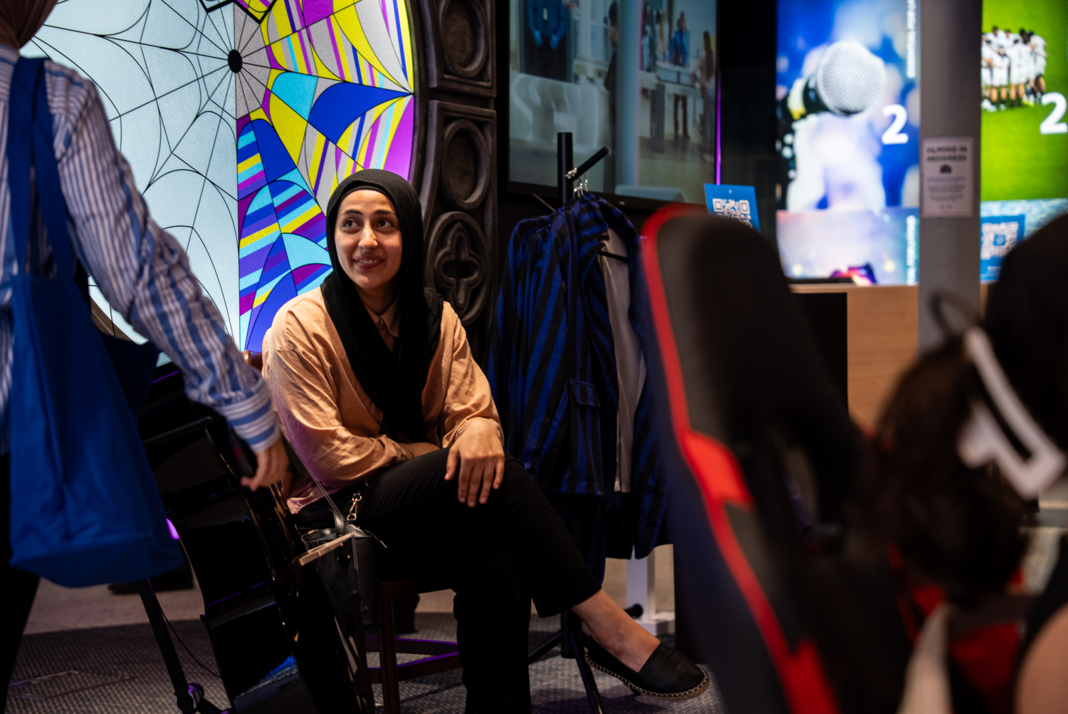 Fan poses in Nevermore Academy dorm room experience inside O2 Priority store, recreating a scene from Netflix's Wednesday series.